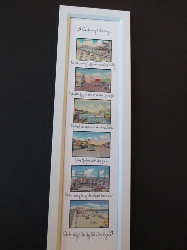 May include: A framed print with a vintage aesthetic featuring a series of black and white postcard images of a beach town. The print includes a handwritten poem about a trip to the beach, with lines like "You looked so very pretty when we went on in Ocean City" and "My heart was gone when we reached Avalon".