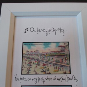 May include: A framed image with a vintage postcard of a boardwalk and beach scene. The text "On the way to Cape May... You looked so very pretty when we met in Ocean City" is written in cursive.