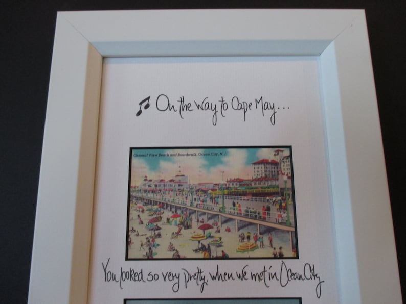 May include: A framed image with a vintage postcard of a boardwalk and beach scene. The text "On the way to Cape May... You looked so very pretty when we met in Ocean City" is written in cursive.