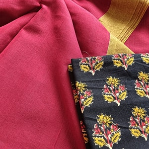 May include: A close-up of a textile arrangement featuring a deep red fabric with a gold border. A folded black fabric with a floral pattern in yellow and red is also visible. The textile is likely used for clothing or home decor.