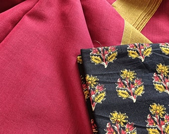 May include: A close-up of a textile arrangement featuring a deep red fabric with a gold border. A folded black fabric with a floral pattern in yellow and red is also visible. The textile is likely used for clothing or home decor.
