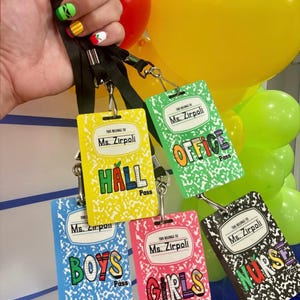 May include: A collection of colorful school-themed passes with black lanyards. Each pass features a notebook design and the text "Ms. Zirpoli" at the top. The passes are labeled "Hall", "Office", "Boys", "Girls", and "Nurse".