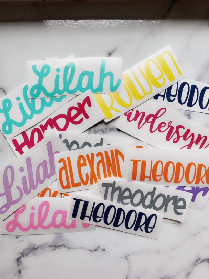 May include: A collection of colorful vinyl stickers with various names written in a cursive font. The names include Lilah, Harper, Ruen, Anderson, Theodore, and Alexand.
