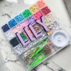 May include: A clear plastic organizer filled with colorful beads, letter beads, and accessories for jewelry making. The name "LILY" is displayed in large purple letters across the center of the organizer. Includes tools and findings.