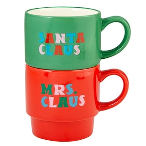 May include: A set of two ceramic mugs, one green and one red. The green mug says "SANTA CLAUS" in colorful letters. The red mug says "MRS. CLAUS" in colorful letters.