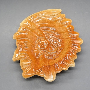 May include: A ceramic dish shaped like an Native American chief's head with a brown glaze.