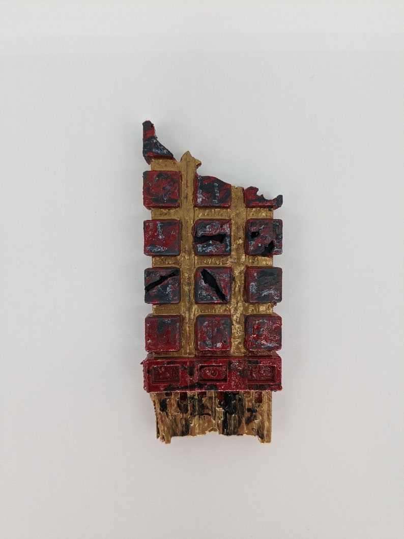 May include: A red and gold miniature building with a distressed finish. The building is made of small squares and has a broken top. The building is a miniature model of a building.