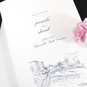 May include: A wedding invitation with a white background and black text. The text reads "Best Day Ever" followed by the names "Pamela and David" and the date "June 1, 2017". The location is listed as "Greenville, South Carolina". The bottom of the invitation features a black and white sketch of a cityscape.