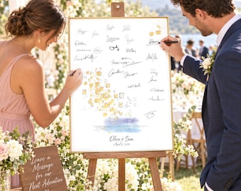 May include: A rectangular wedding guest book sign in a gold frame on a wooden easel, featuring a watercolor illustration of floating lanterns, numerous guest signatures, and the text Olivia & Sam April 8, 2027, with a wooden sign reading Leave a Message.