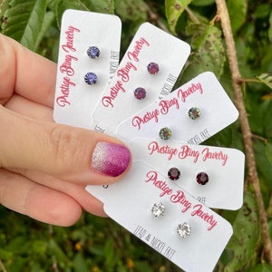 May include: Five pairs of small, round, colorful earrings on white cards with the text "Prestige Bling Jewelry" and "Lead & Nickel Free".