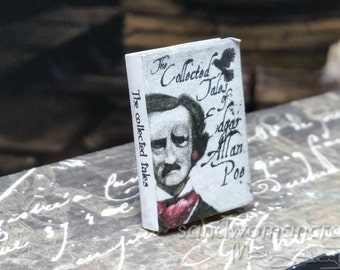 May include: Miniature book titled "The Collected Tales of Edgar Allan Poe." The book has a white cover with a portrait of Poe and a black bird illustration. The spine reads "The collected tales."