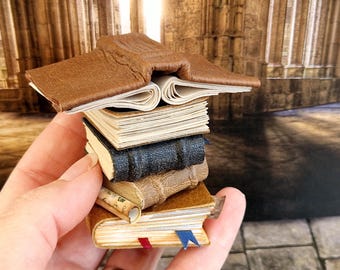 May include: A stack of miniature books with a brown leather cover on top. The books are arranged in a hand, with the top book open and the pages fanned out.