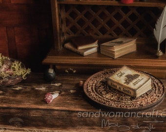May include: A miniature book titled "Book of Spells" with a black and white illustration of a dragon on the cover, resting on a circular wooden base with intricate carvings.
