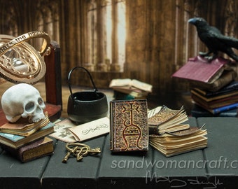 May include: A miniature collection featuring a gold-toned hourglass on a stand, a white skull, a black cauldron, several small leather-bound books with intricate gold detailing, a set of metal keys, and a black raven figurine perched on a stack of books.