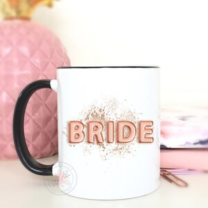 Puede incluir: Taza de cer&aacute;mica blanca con asa negra. La taza tiene un dise&ntilde;o de purpurina dorada rosa y la palabra "BRIDE" en letras doradas rosas.
