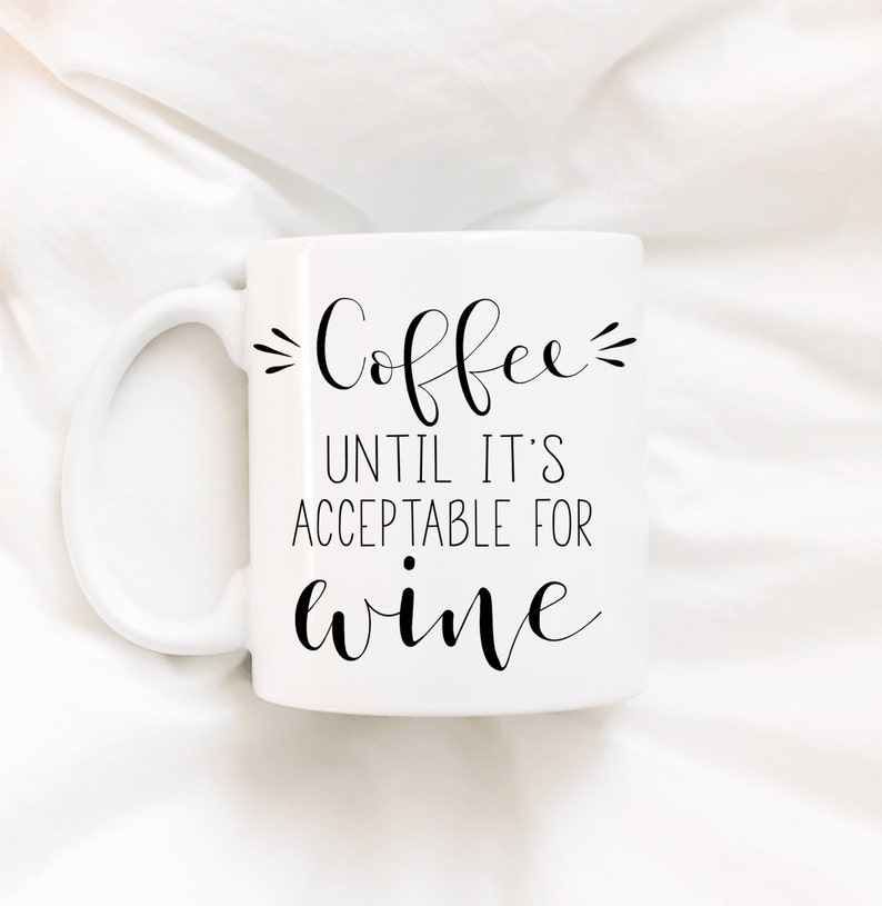 May include: White coffee mug with black text that reads "Coffee until it's acceptable for wine".