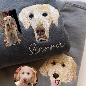 Op de afbeelding: Twee grijze sweatshirts met op maat geborduurde hondenportretten. E&eacute;n sweatshirt heeft een portret van een golden retriever met de naam "Sierra" eronder geborduurd. De andere heeft een vergelijkbaar portret met de naam "Bruce".
