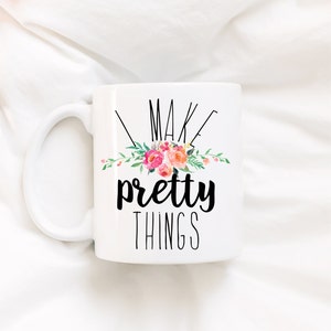 May include: White ceramic mug with a black floral design and the text "I make pretty things".