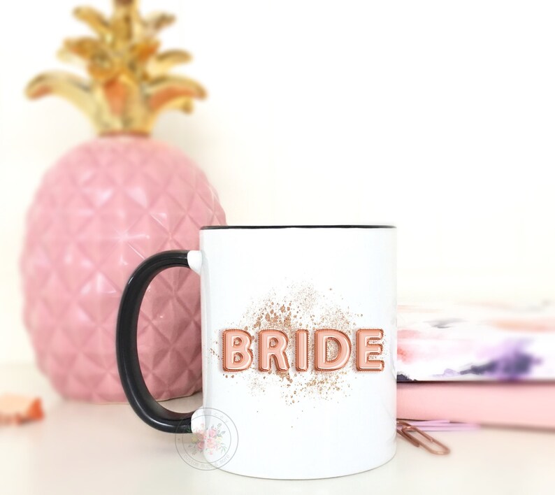 Puede incluir: Taza de cer&aacute;mica blanca con asa negra. La taza tiene un dise&ntilde;o de purpurina dorada rosa y la palabra "BRIDE" en letras doradas rosas.