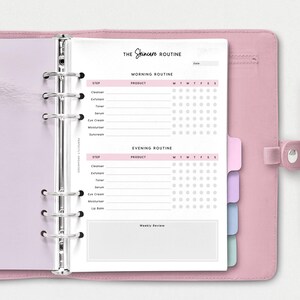 May include: A pink and white planner with a tabbed section for a skincare routine. The planner has a section for morning and evening routines, with a checklist for each step. The planner also has a section for weekly reviews.
