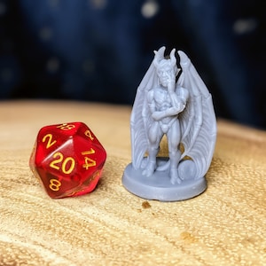 May include: A gray miniature figurine of a demon with wings, standing on a gray base. The demon is holding its chin in thought. A red twenty-sided die with gold numbers is in the foreground.