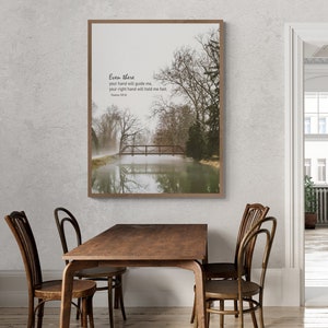 May include: A framed print with a quote from Psalm 139:10, "Even there your hand will guide me, your right hand will hold me fast." The print features a photograph of a wooden bridge over a misty river in a forest.