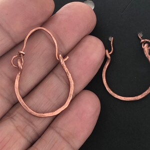 May include: A pair of copper hoop earrings with a hammered finish. The earrings are simple and elegant, and would make a great gift for any occasion.