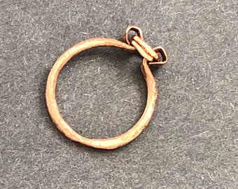 Op de afbeelding: Een eenvoudige, gehamerde koperen ring met een klein, decoratief sluiting.