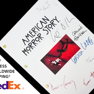 May include: A white script with the title "American Horror Story" and the text "We  O.I.L" in black. The script is signed by several people, including Jessica Lange, Connie Britton, and Taissa Farmiga. The script features a photo of a scene from the show.