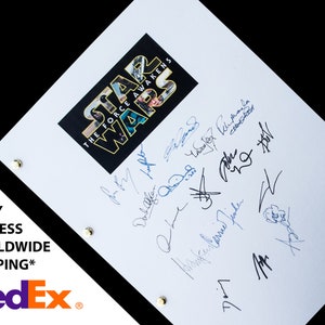 May include: A white sheet of paper with a black and white Star Wars: The Force Awakens logo in the upper center. The paper is signed by multiple people in blue and black ink.