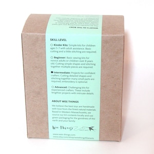 May include: A rectangular brown cardboard box featuring a light green paper band wrapped around it. The band contains printed text detailing skill levels, including Kinder, Beginner, Intermediate, and Advanced, along with company information.