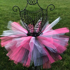 May include: A pink, black and white tulle tutu skirt on a mannequin. The skirt is layered and fluffy.