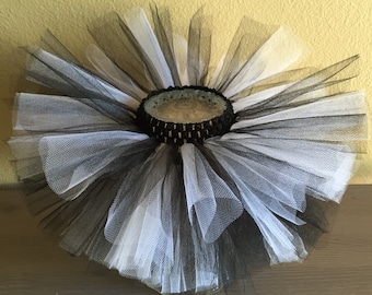 May include: Black and white tulle tutu with a black elastic waistband. The tutu is made of multiple layers of tulle and is perfect for a party or special occasion.