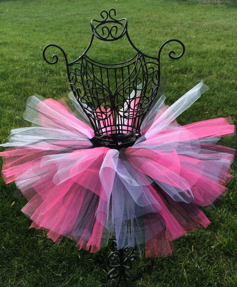 May include: A pink, black and white tulle tutu skirt on a mannequin. The skirt is layered and fluffy.