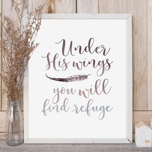 Könnte beinhalten: Weißer gerahmter Druck mit dem Text "Unter seinen Flügeln findest du Zuflucht" in einer lila und grauen Farbverlaufschrift. Eine lila und graue Feder befindet sich über dem Text.