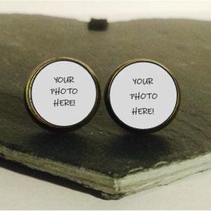 May include: Two round, white, button-like cufflinks with a gold rim. The cufflinks have the text "YOUR PHOTO HERE!" printed on them.