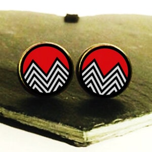 May include: A pair of round, red and black earrings with a geometric mountain design.