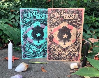 May include: Two booklets with the text "Witch Tips" and "For Spells for Whatever" are displayed. One booklet is teal, the other is peach. Both feature a black cauldron with a star. A white candle and crystals are in the foreground.
