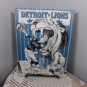Può includere: Un programma di gioco di football americano vintage dei Detroit Lions del 29 ottobre 1961, con un leone di cartone animato e un giocatore di football sullo sfondo. Il programma pubblicizza una partita contro i Los Angeles Rams al Los Angeles Memorial Coliseum per 25 centesimi.