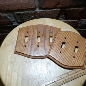 Könnte beinhalten: Zwei Holz-Lichtschalterplatten mit abgerundeter Kante. Die größere Platte hat drei Schalteröffnungen und die kleinere Platte hat zwei Schalteröffnungen.