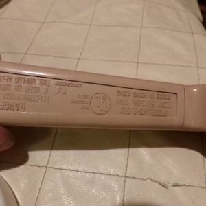 May include: A beige plastic electrical appliance with a warning label that reads "DANGER Electrocution Possible If Used or Dropped in Tub. Unplug After Using." The label also includes the text "MODELAG-2/960 MADE IN HONG KONG UL LISTED", and a UL symbol.