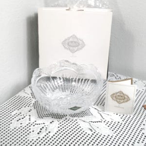 Könnte beinhalten: Eine klare Kristallschale mit gewelltem Rand und strukturiertem Design. Die Schale wird mit der Originalverpackung und einer kleinen Karte präsentiert. Die Schale dient wahrscheinlich Dekorations- oder Servierzwecken.