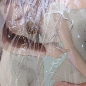 May include: Two women wearing white dresses with lace trim. The dresses are sheer and the women's bodies are visible through the fabric. The women are standing close together and their arms are wrapped around each other.
