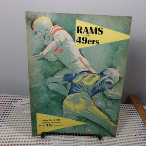 Può includere: Una copertina di programma di football vintage con un'illustrazione gialla e verde di due giocatori di football in azione. Il testo "RAMS vs. 49ers" è stampato in nero su un triangolo giallo. Il programma è datato "domenica 4 dicembre 1960" e costa "25c".