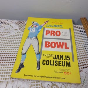 May include: Vintage 1961 Pro Bowl program with a yellow cover. The cover features a football player in a blue uniform throwing a football. Text includes "All-Star Football", "East vs West", "Sunday Jan. 15 Coliseum".