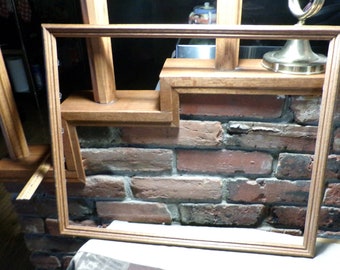 May include: A wooden picture frame with a brown finish sits on a brick wall. The frame is empty and ready for a picture.