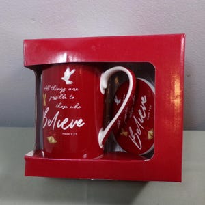May include: A red mug with a white handle and a white dove design. The mug has the text "All things are possible to those who Believe Mark 9:23" printed on it. The mug is packaged in a red box with a matching coaster.