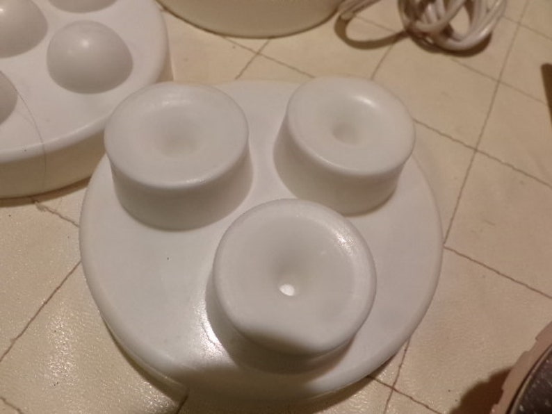 May include: White plastic base with three round attachments, each with a small hole in the centre. The base is designed to hold the attachments securely.