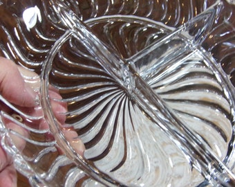 Può includere: Piatto da portata in vetro trasparente con un design diviso. Il piatto presenta un bordo smerlato e una sezione centrale divisa in quattro scomparti. Il vetro presenta un motivo a spirale che si irradia dal centro.