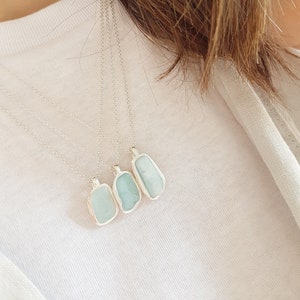 May include: Four silver necklaces with light blue aquamarine stone pendants. The pendants are rectangular and have a natural, irregular shape.
